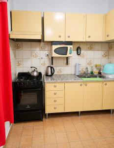 a kitchen with a stove and a microwave at Casa RAU-JO in Guaymallen