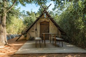 a tent with a table and chairs on a wooden deck at Logement insolite glamping tipi et lodge Var Grimaud in Grimaud