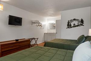 a hotel room with two beds and a television at Trailhead Lodge in Eureka Springs
