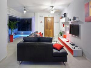 a living room with a black couch and a tv at Villa Sunnyside in St. Julianʼs