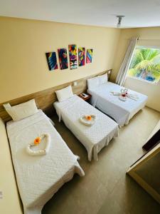 a hotel room with two beds and a window at Pousada Donna Maraka in Porto De Galinhas +33 photos