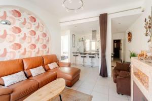 a living room with a brown leather couch and a kitchen at Au Moulin d'Or in Lille