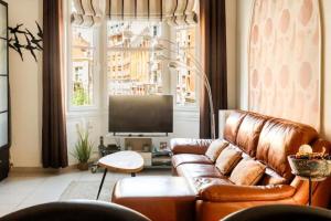 a living room with a brown leather couch and a television at Au Moulin d'Or in Lille
