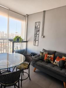 a living room with a couch and a glass table at Studio Pôr do Sol - Garagem - Piscina - Anhembi in São Paulo