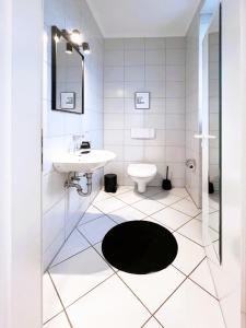 a white bathroom with a sink and a toilet at Ferienwohnung Ostseeglück in der Villa Marie in Kühlungsborn +4 photos