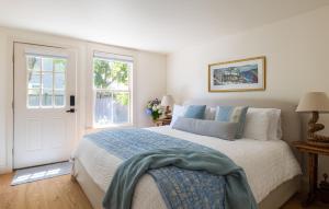 a white bedroom with a large bed and two windows at The Lightkeeper’s Inn in Edgartown
