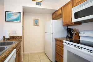 a kitchen with a white refrigerator and a sink at Keys Waterfront Condo with Beach Pool Sunset Views in Tavernier