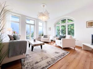 a living room with white furniture and large windows at Ferienwohnung Ostseeglück in der Villa Marie in Kühlungsborn
