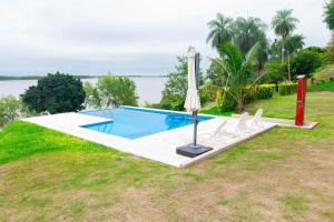 a swimming pool with chairs and an umbrella at Habitacion en Cabañas Bella vista in Bella Vista