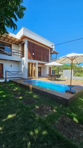 a house with a swimming pool and an umbrella at White House - Taipú de Fora in Barra Grande