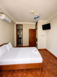 a bedroom with a large white bed and a television at La Posada Del Pajarito in Yurimaguas
