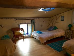 Un dormitorio con dos camas y una silla y una ventana. en Occitania B&B, en Puivert