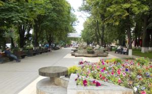 people sitting on benches in a park with flowers at Apartament Central Pietonalul Unirii in Botoşani