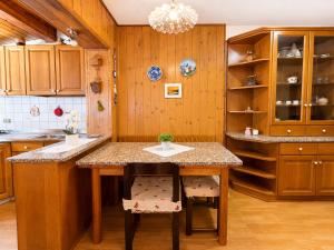 a kitchen with wooden cabinets and a table with chairs at Zoncolan Mountain Lodge - Ride & Ski in Timau