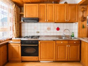 a kitchen with wooden cabinets and a stove and a sink at Zoncolan Mountain Lodge - Ride & Ski in Timau