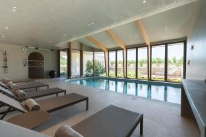 an indoor pool with tables and chairs and windows at La Villa des Vignes in Saint-Émilion