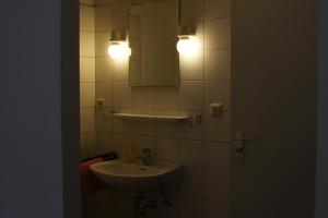 a bathroom with a sink and a mirror and lights at Wolfcenter Gästezimmer in Dörverden