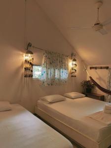 two white beds in a room with a window at Mar Amar Casa de Playa in Coveñas