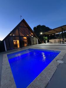 a blue swimming pool in front of a building at Alpine River Cabin with direct access to the river in Río Arriba