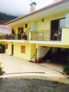 ein großes gelbes Gebäude mit einem Balkon und einer Treppe in der Unterkunft Residência Iris in Geres