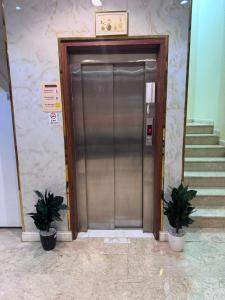 a metal elevator door in a building with two plants at سحابه صيف للشقق المخدومه - حي الاندلس - in Abha