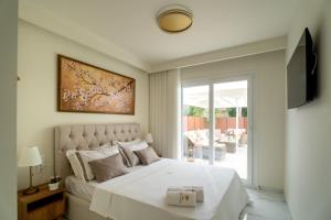 a bedroom with a large white bed and a television at Halkidiki Luxury Villa Palm Oasis Private Pool & Hot Tub in Nea Irakleia +31 photos