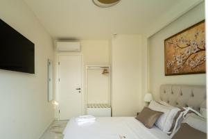 a white bedroom with a bed and a television at Halkidiki Luxury Villa Palm Oasis Private Pool & Hot Tub in Nea Irakleia