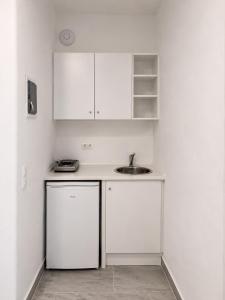 a kitchen with white cabinets and a sink at Orama suite I in Mikonos