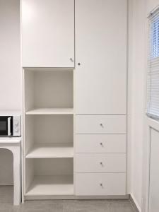 a white closet with white drawers and a microwave at Orama suite I in Mikonos