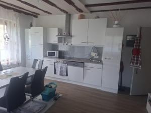 a kitchen with white cabinets and a table with chairs at Haus Steiner in Kleblach
