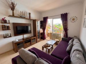 a living room with a purple couch and a tv at Mar y piscina in Cabo Negro