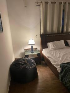 a bedroom with a bed and a table with a lamp at Executive Guest Room - Helcion Residency in Lahore