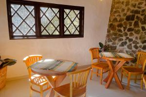 a dining room with a table and chairs and a window at VELINN Pousada Canto da Cascata in Camanducaia