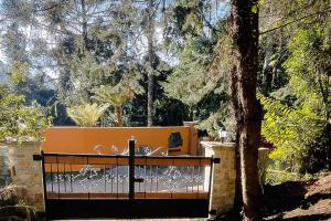 a black gate in front of a tree at VELINN Pousada Canto da Cascata in Camanducaia +5 photos