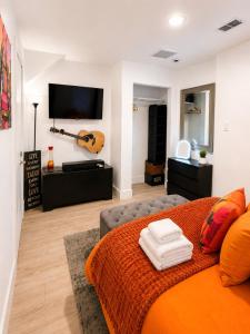 a living room with a couch and a guitar on the wall at Quiet & Centrally located House - PRIVATE PARKING, LAUNDRY AND STORAGE FOR LUGGAGE in Miami
