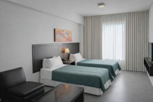 a hotel room with two beds and a chair at Hotel NEU 354 in Neuquén +50 photos