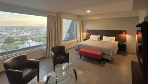 a hotel room with a bed and two chairs at Hotel NEU 354 in Neuquén