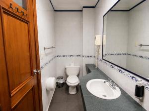 a bathroom with a toilet and a sink and a mirror at Cavi Rooms 305 in Cuenca