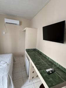 a room with a tv on the wall and a bed at Hotel Coqueiral in Recife