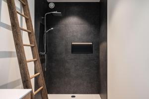 a shower in a bathroom with a black wall at Gîte de Thibautienne in Gedinne
