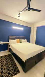 a bed in a room with a blue wall at Omaxe Hazratganj Stay in Lucknow +5 photos