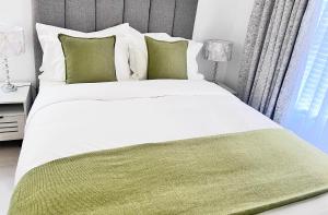 a bedroom with a large white bed with green sheets and pillows at The cozy garden suites in Sandton
