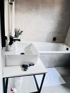 a bathroom with a white sink and a bath tub at The cozy garden suites in Sandton +16 photos