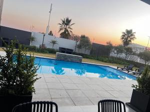 a swimming pool with two chairs and palm trees at The cozy garden suites in Sandton