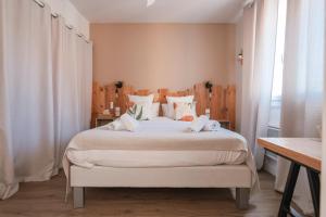 a bedroom with a large white bed with white curtains at Hôtel La Baïne in Capbreton