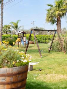 a swing set in a park with palm trees at B&B Villa Mamma Grazia in San Vito dei Normanni
