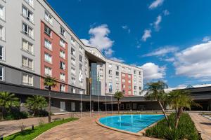 an exterior view of a building with a swimming pool at Hotel Deville Prime Porto Alegre in Porto Alegre