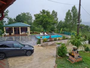 a car parked in front of a house with a swimming pool at Casa de vacanta La Fane in Valcea