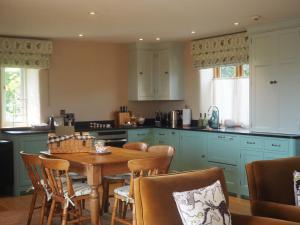 a kitchen with blue cabinets and a table and chairs at Hobbs Hole Cottage & Studio in Great Tew