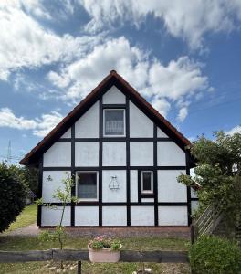 a white and black house with a roof at Ruhiges Elbhäuschen nahe Hamburg in Hollern-Twielenfleth
